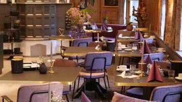 Un restaurant avec des tables rondes et des chaises violettes, doté d’un intérieur en bois et d’une grande fenêtre.