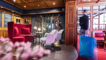 Eine Hotelhalle mit einem roten Sofa, einem runden Tisch und einer Bar.