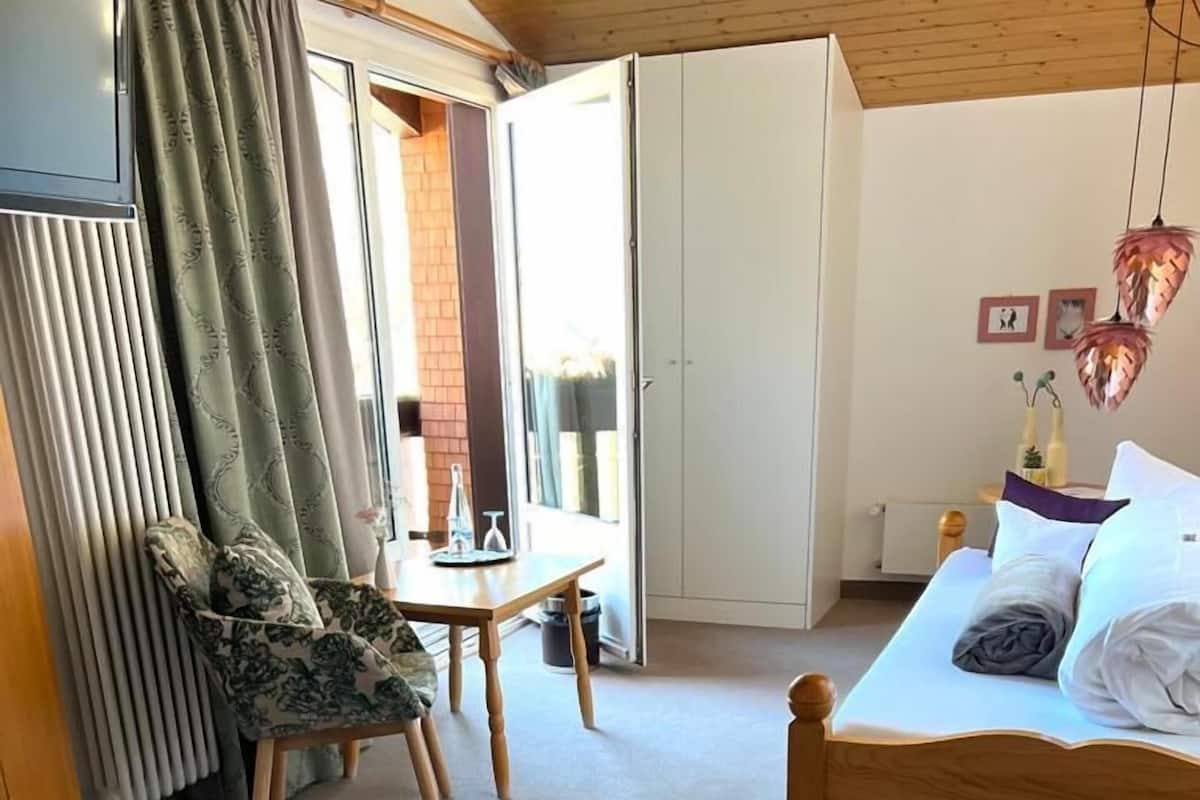 Een slaapkamer met een bed, een stoel, een tafel en een televisie.