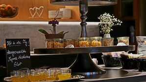 Een buffetopstelling met een etagère, glazen containers met eten, en een bord met tekst.
