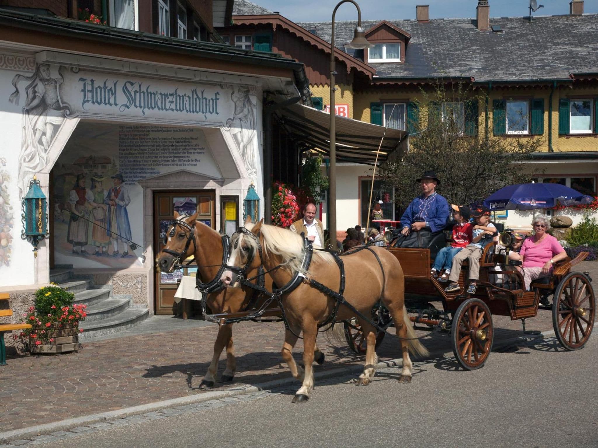 A horse-drawn carriage in front of a building with a sign reading 'Hotel Schwarzwaldhof'.