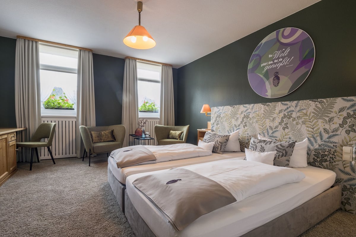 Een hotelkamer met twee bedden, een bureau, een stoel en een raam met gordijnen.