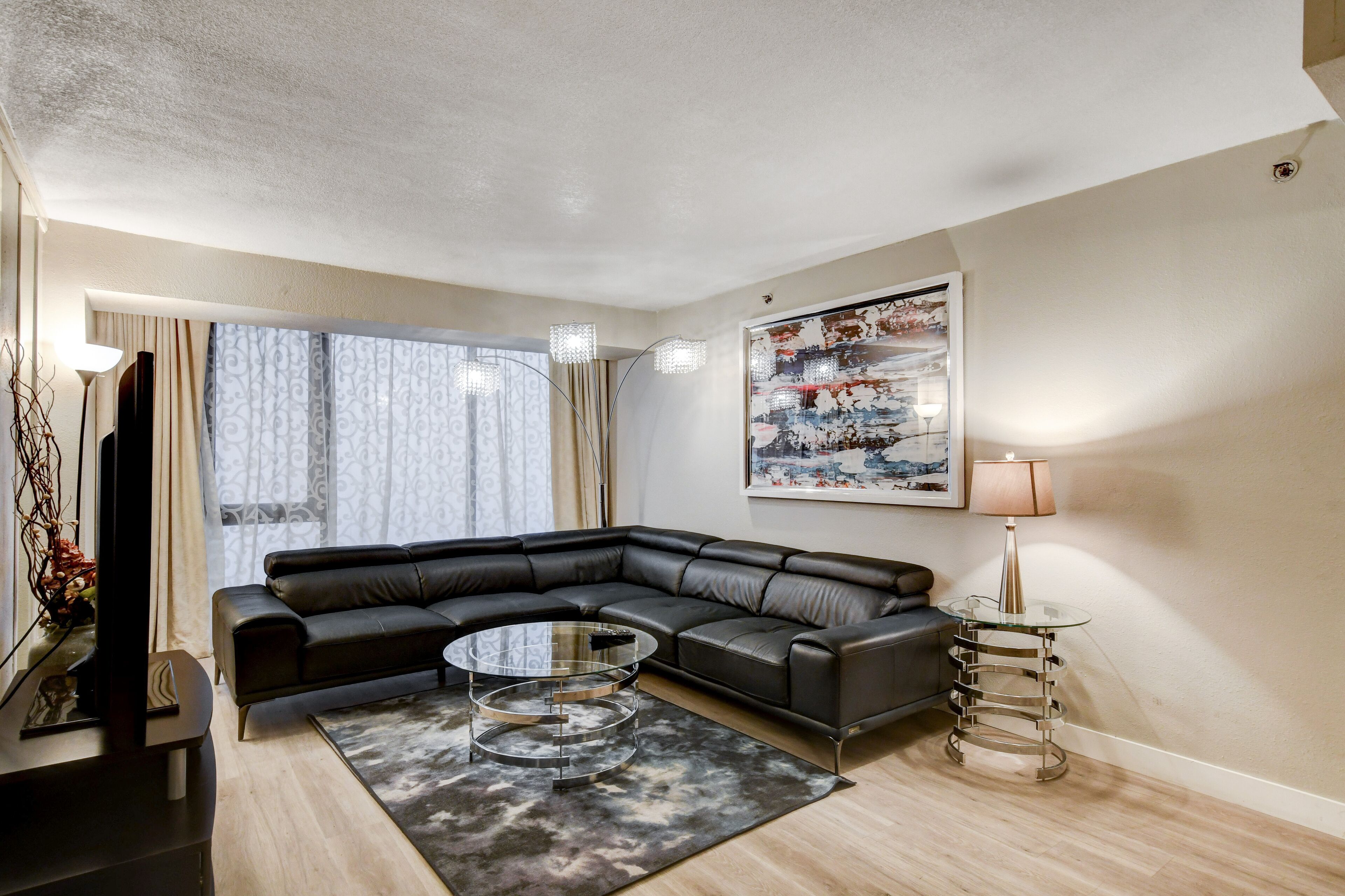 Ein modernes Wohnzimmer mit einem Ecksofa, einem Glastisch und einem Bild an der Wand.
