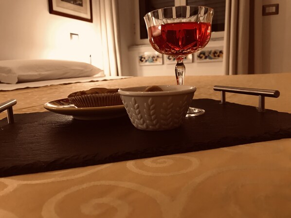Una mesa con un vaso de bebida roja, un cuenco de galletas y un plato de cupcakes.