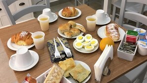 Una tavola imbandita per la colazione con diversi cibi, tra cui pasticcini, uova e un distributore di bevande.