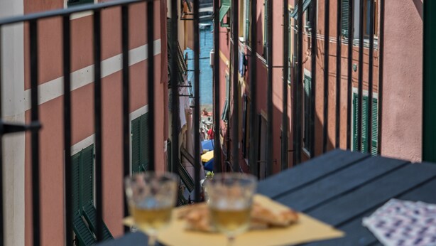 A balcony with a table set for two, glasses of beer, and a deck of playing cards. - El Nin Apartment with Terrace & AC (Vernazza)