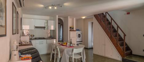Un espace de vie compact comprenant un coin repas, une cuisine et un escalier menant à un niveau supérieur.