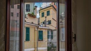 A narrow street view through a window with buildings featuring green shutters and balconies. - El Nin Apartment with Terrace & AC (Vernazza)