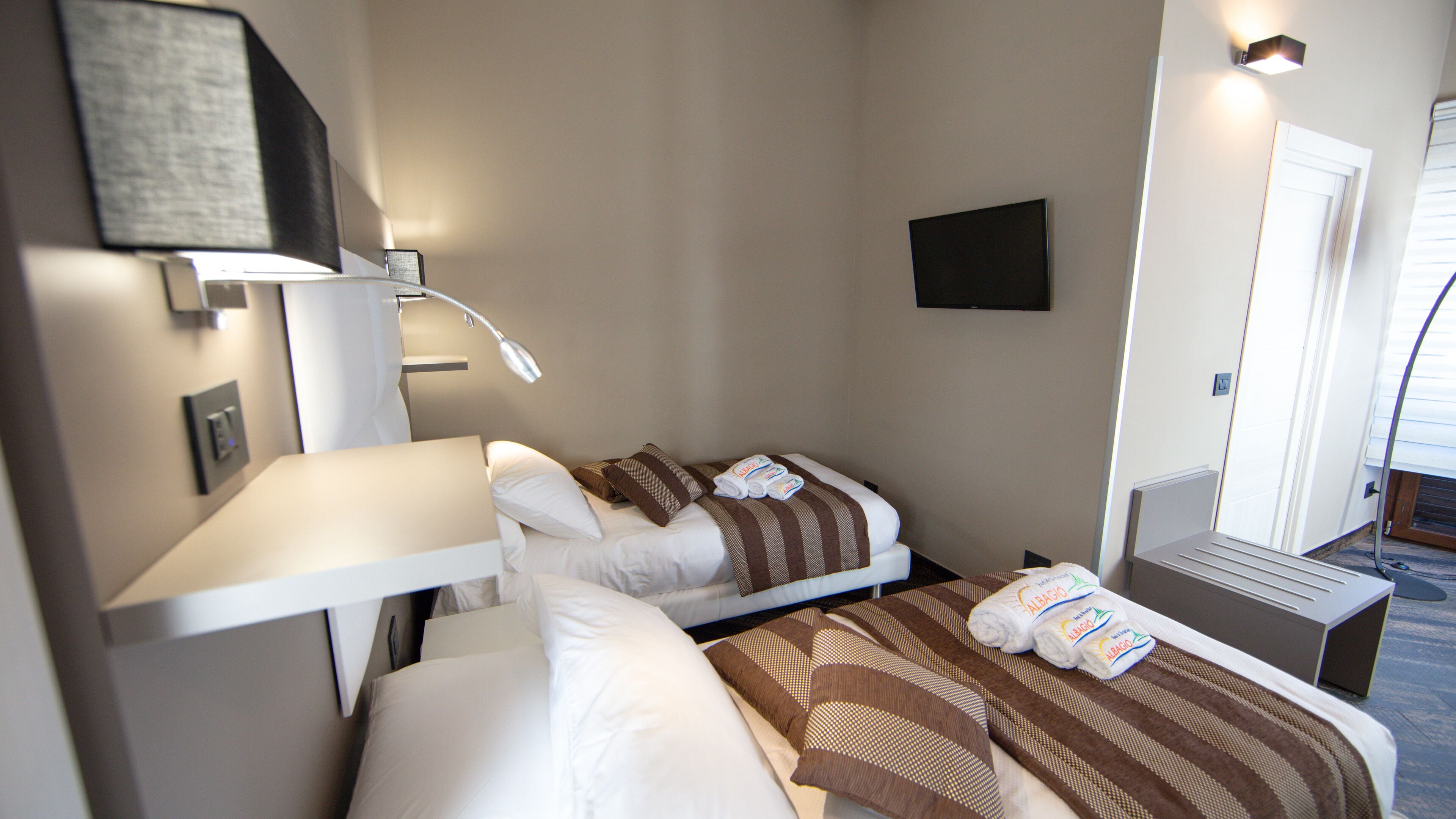 Een hotelkamer met twee bedden, een televisie, een bureau en een raam.
