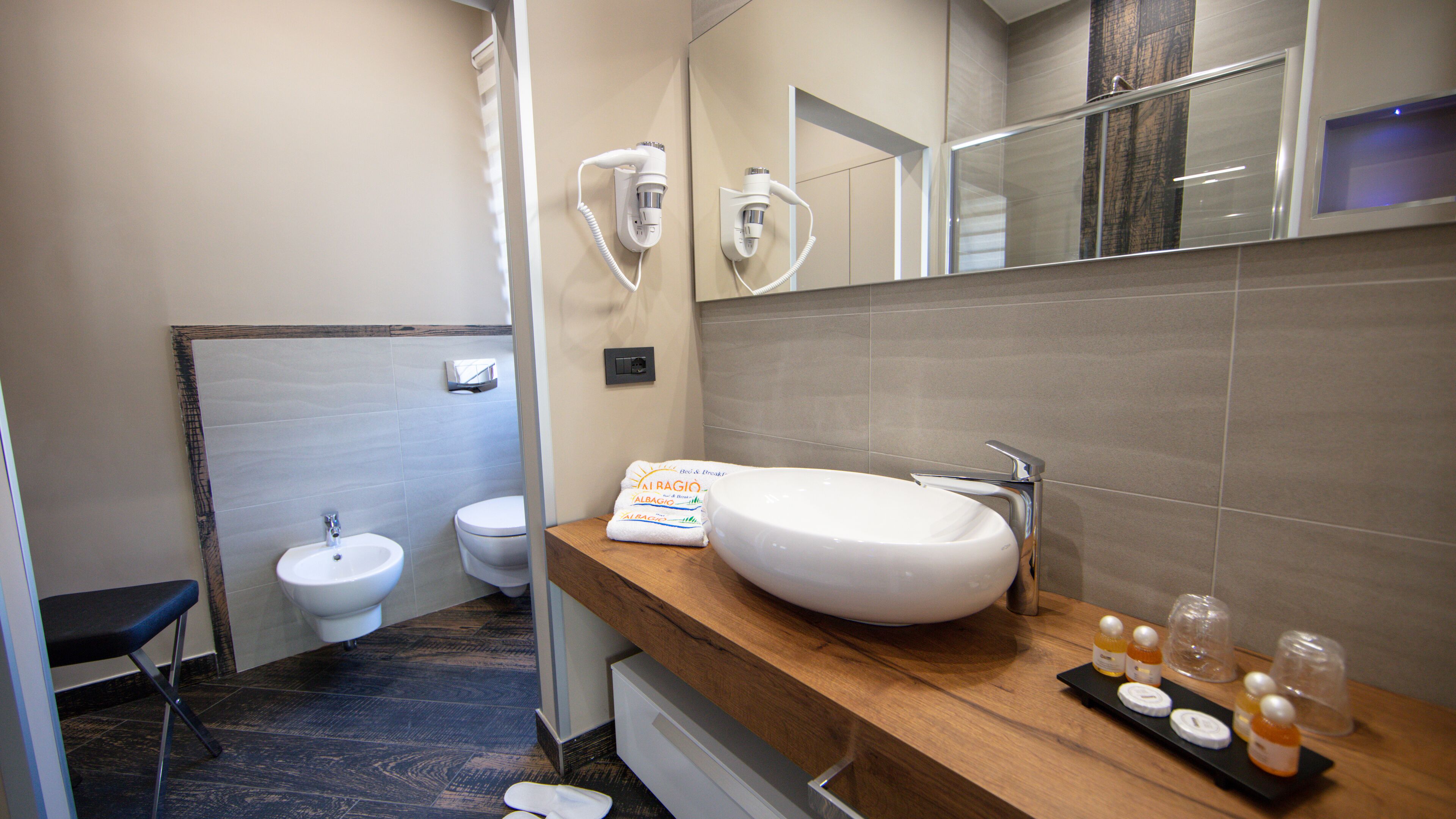 Un baño moderno con un lavamanos grande blanco, un bidé y un mueble de tocador de madera.