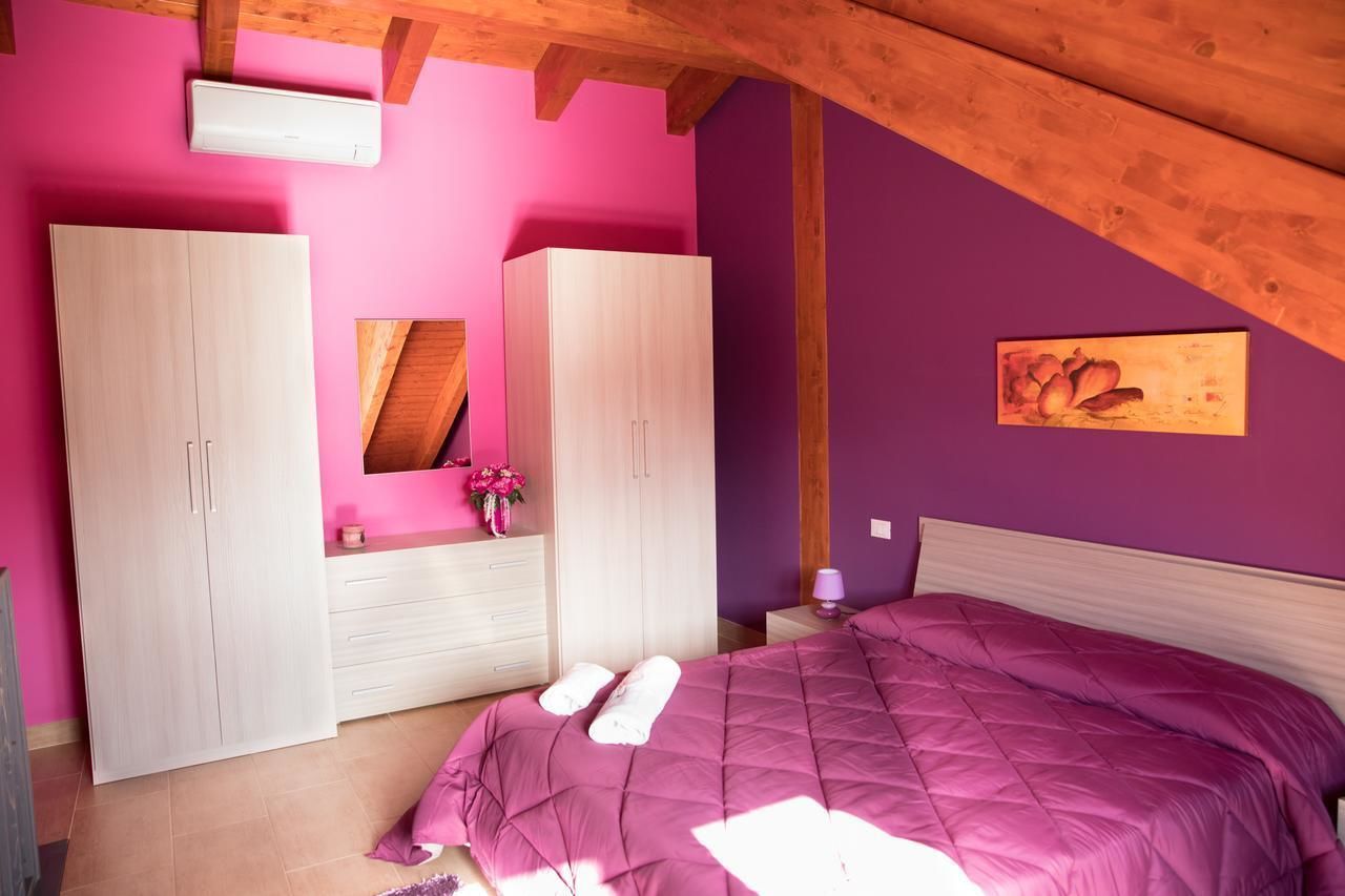 Un dormitorio con cama, dos armarios, un espejo, una mesita de noche y una obra de arte colgada en la pared.