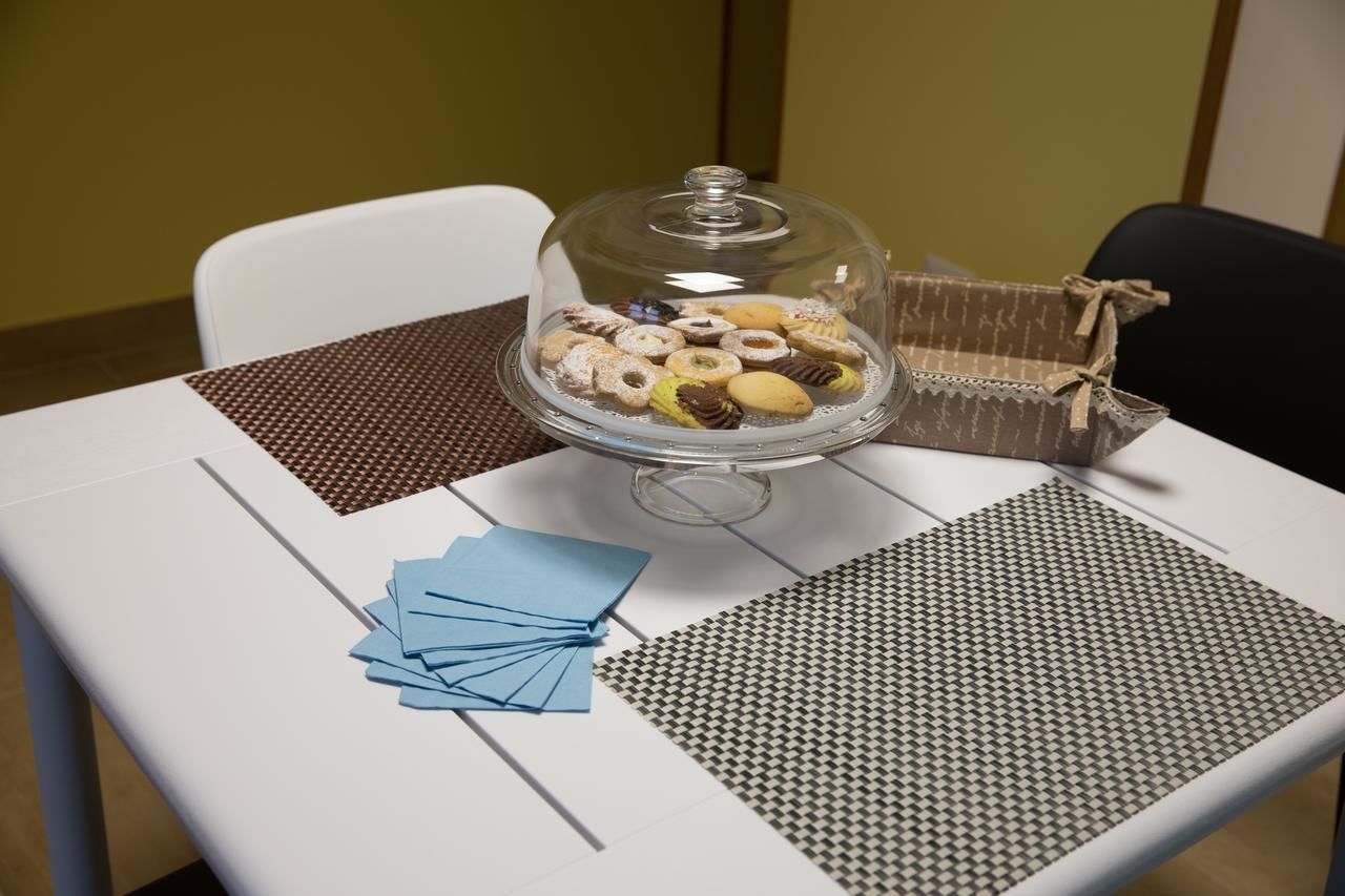 Un tavolo con una vetrina a cupola per dolci, un sottopiattino decorato e tovaglioli azzurri.