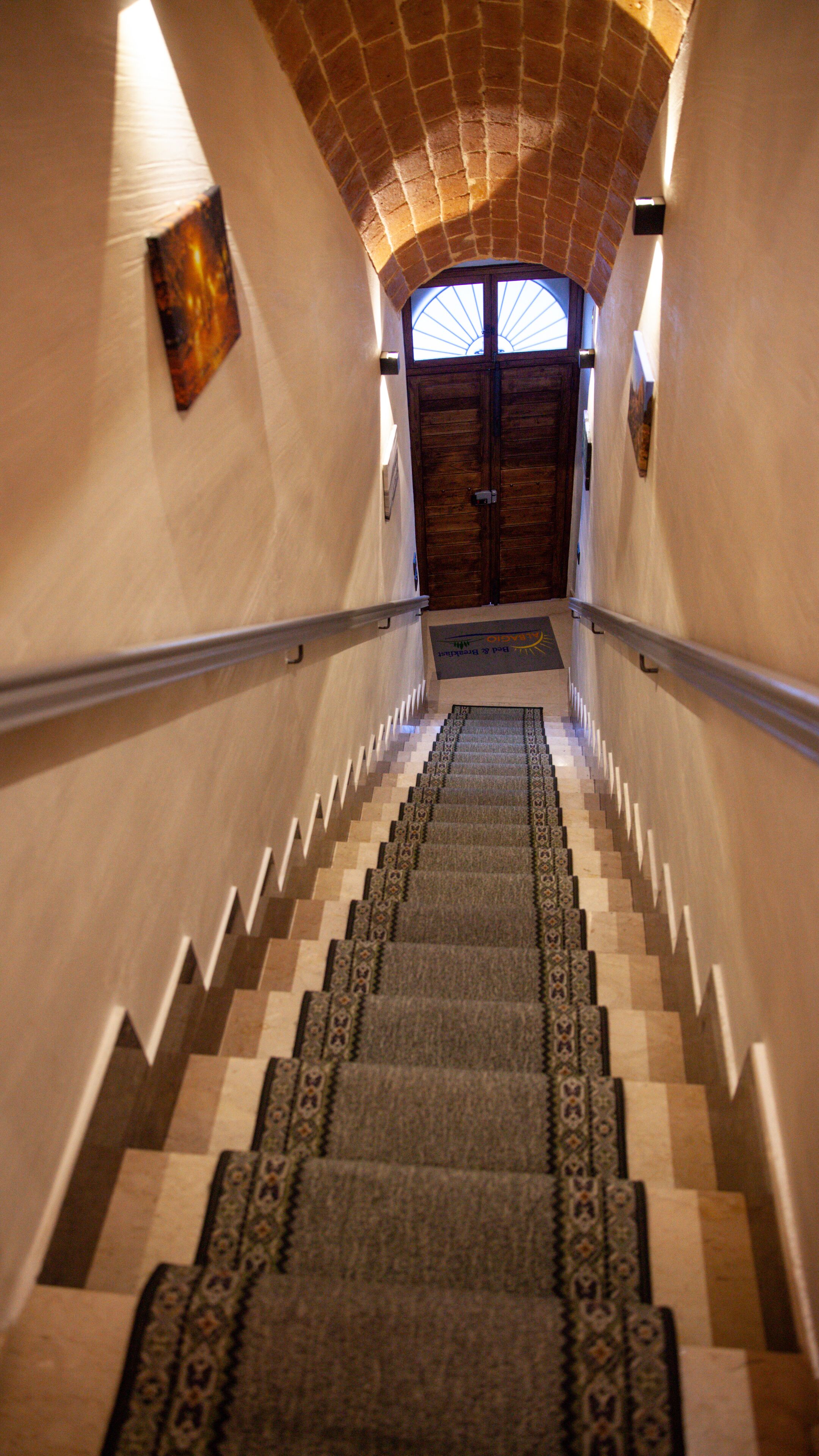 A staircase with patterned carpet leading to a wooden door with glass panels.