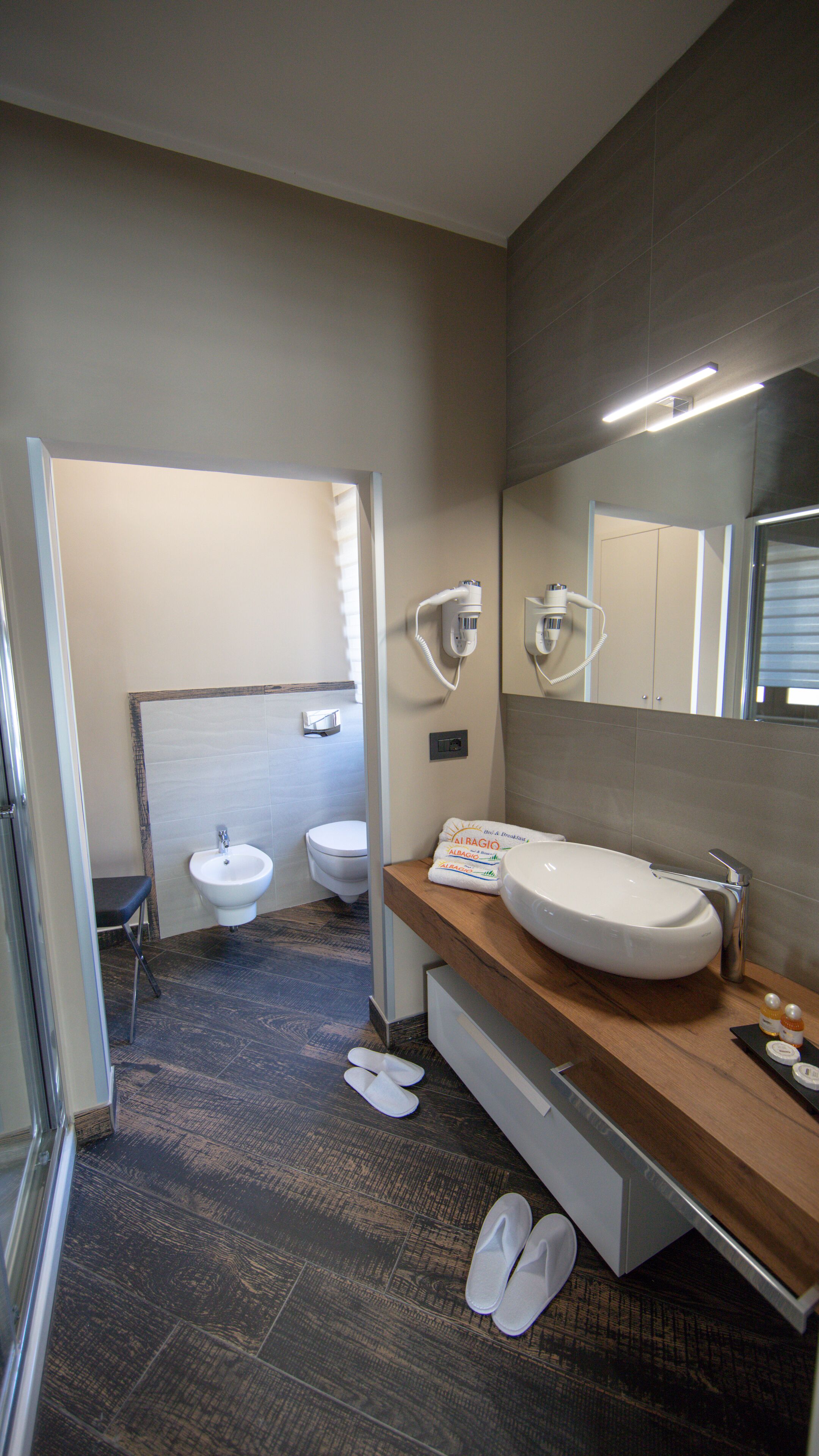 Une salle de bain moderne avec un grand miroir, deux lavabos et une douche.