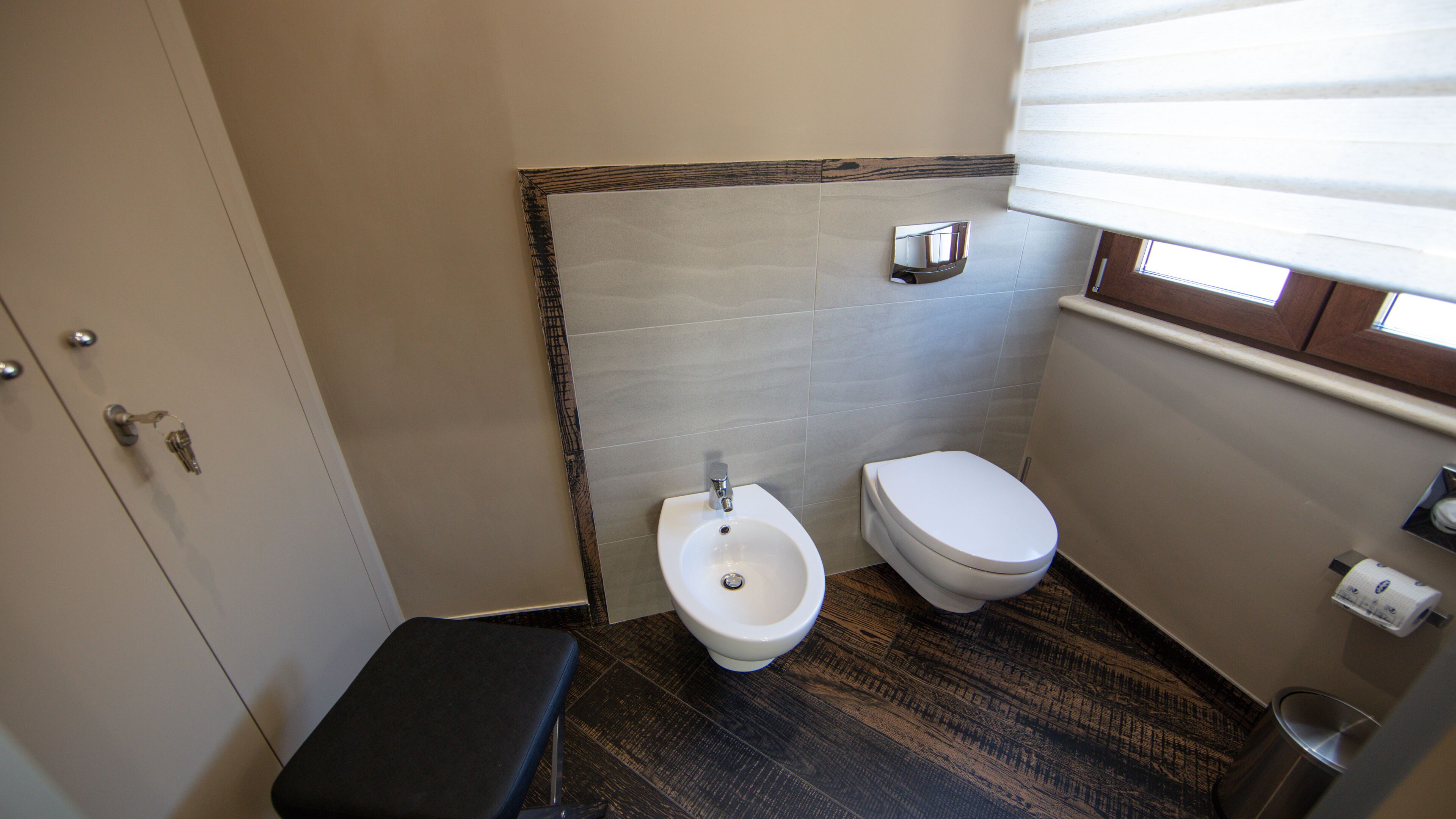 A small bathroom with a bidet, toilet, and a bench.