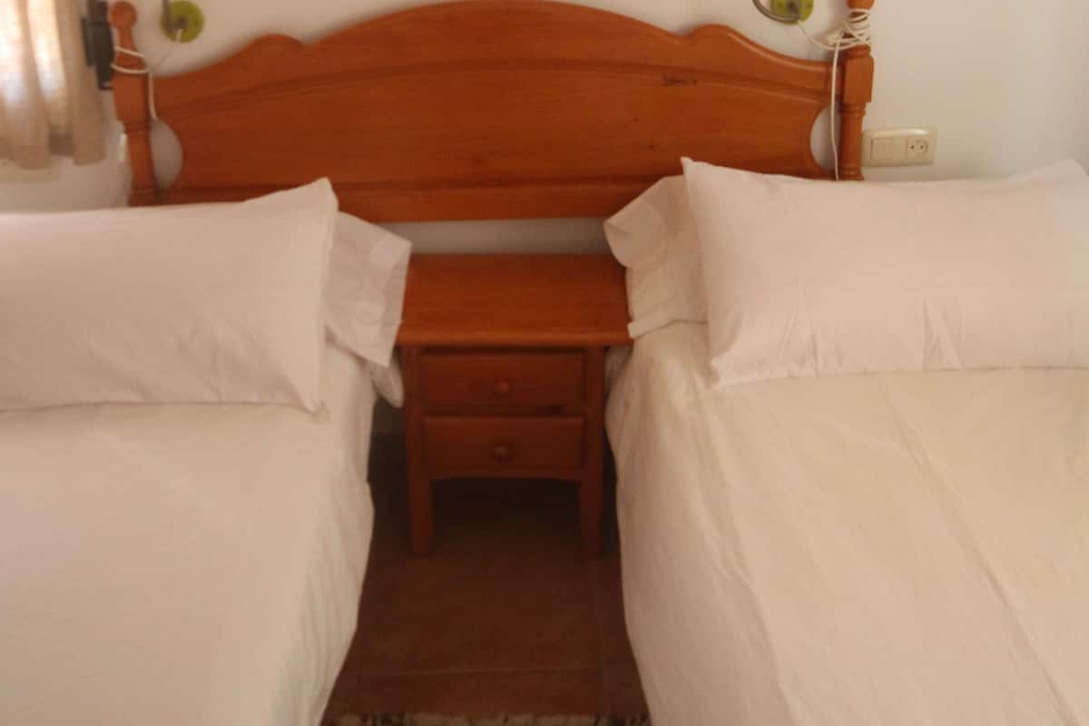 A room with a wooden bed, two bedside tables, a small bench, and wall-mounted artwork of birds.