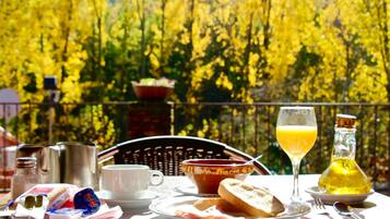 Una mesa de desayuno con diversos alimentos y bebidas, con un fondo de follaje amarillo.