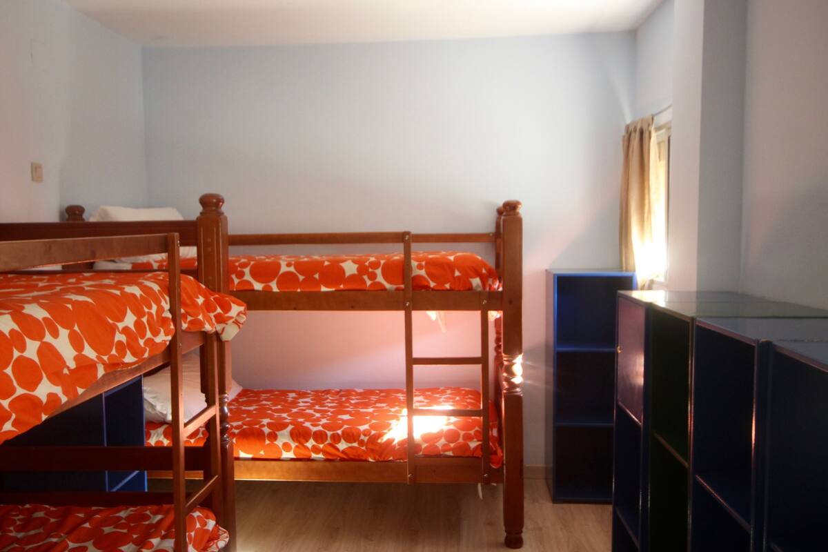 A bunk bed room with a wooden frame and orange patterned bedding.