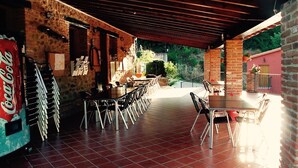An outdoor dining area with brick walls, tiled flooring, and metal chairs. - Hostel El Lago Caceres (Cuacos de Yuste)