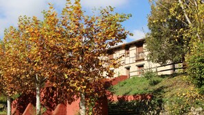 A building with a red exterior and a staircase leading up to it. - Hostel El Lago Caceres (Cuacos de Yuste)