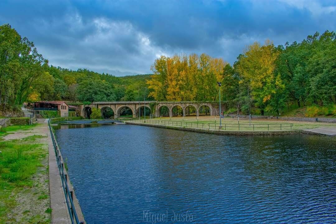 A canal with a stone bridge and a small building on the left.