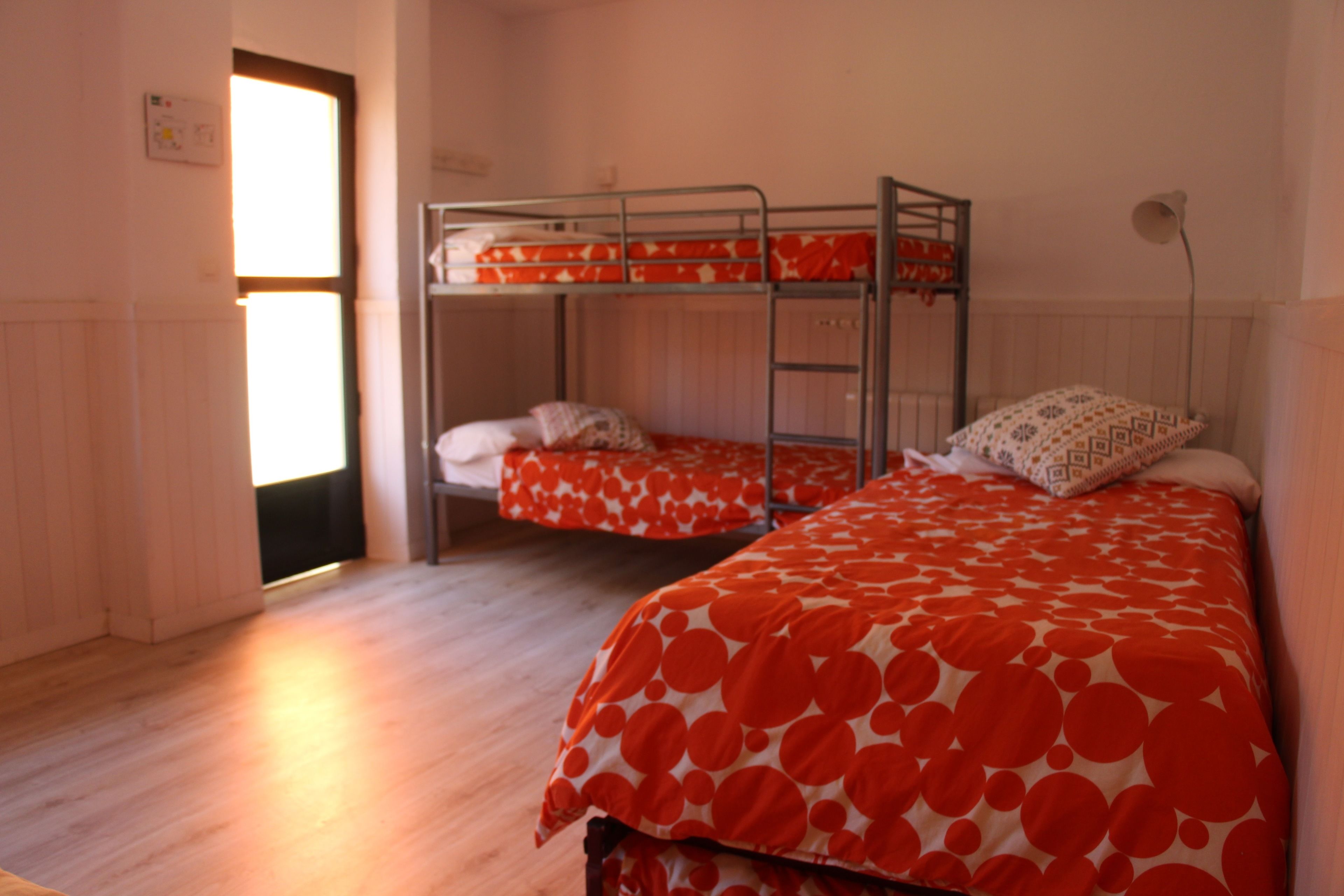 Un dormitorio con literas, suelo de madera y un radiador.