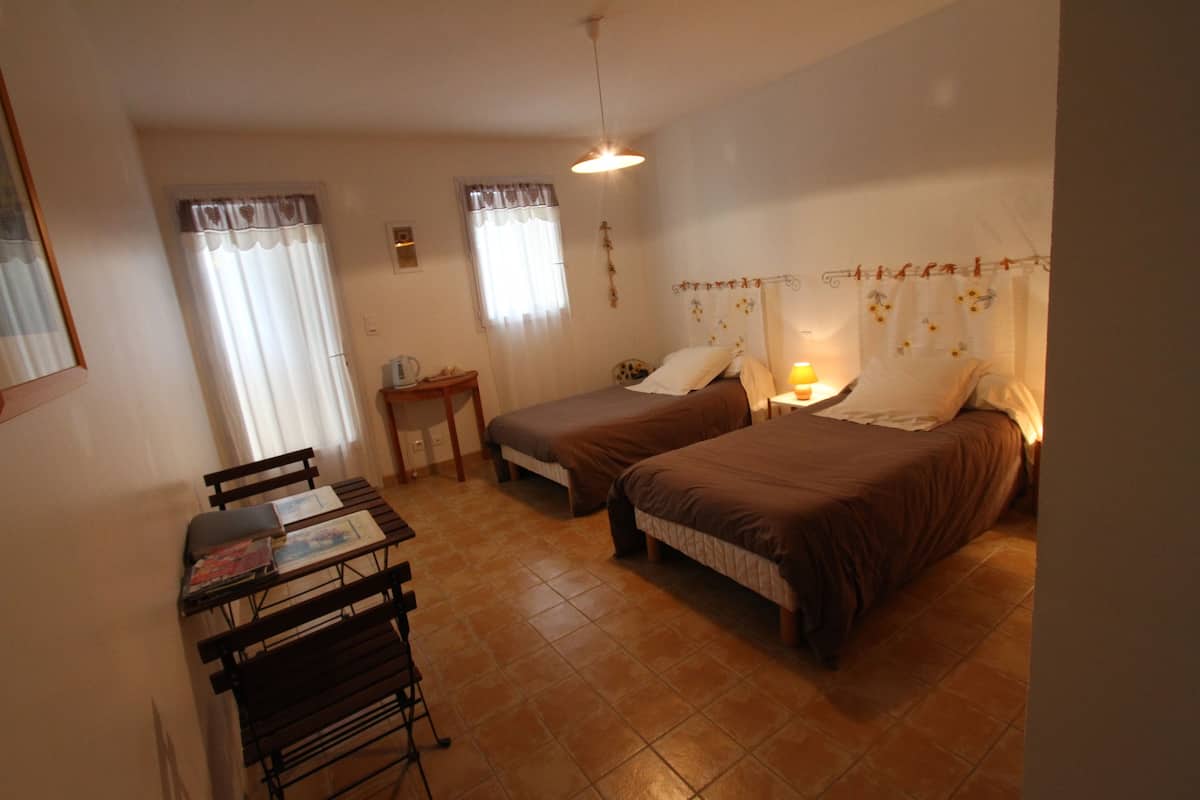 A bedroom with two beds, a desk, and a chair.