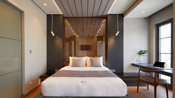 Un dormitorio moderno con cama, mesita de noche y escritorio con silla.