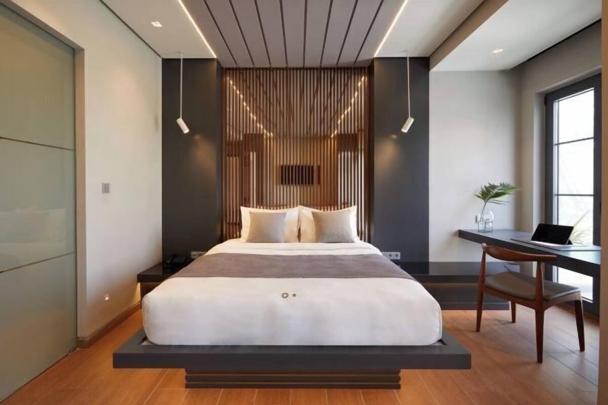 Ein modernes Schlafzimmer mit einer schwebenden Bettkonstruktion, einem Schreibtisch und einem großen Fenster.