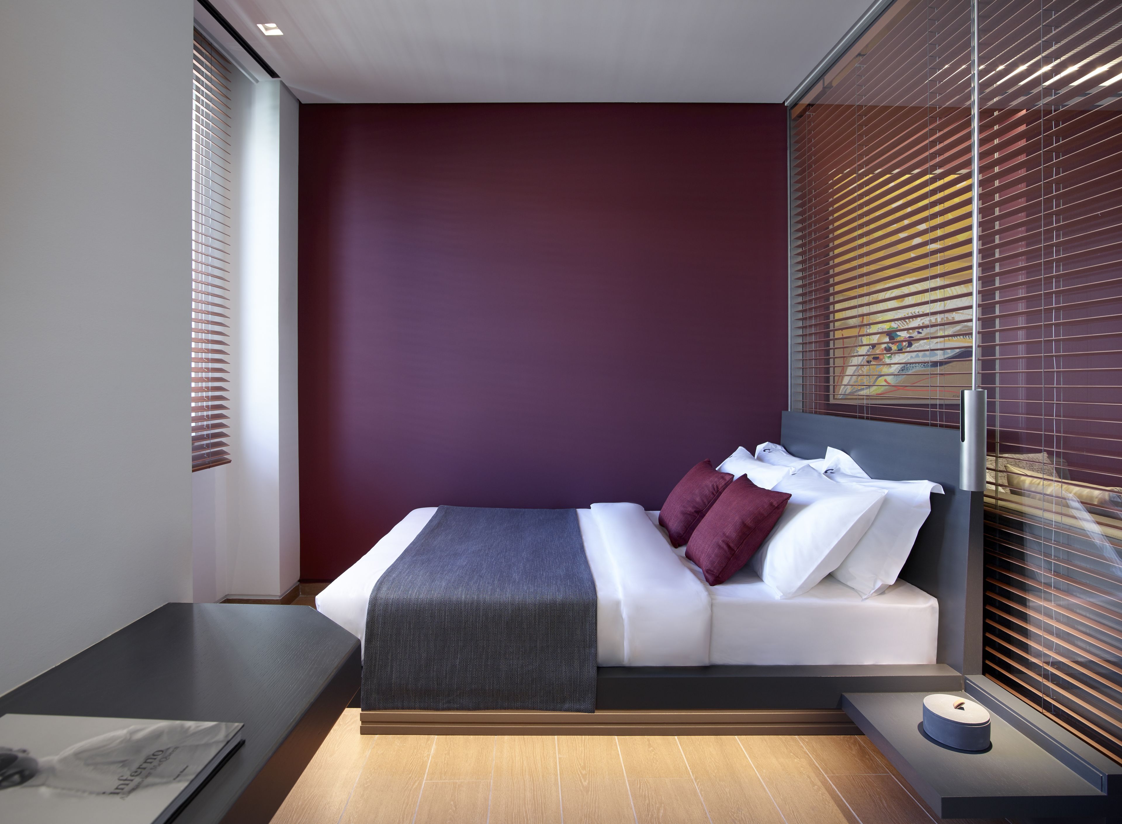Un dormitorio moderno con cama, mesitas de noche y ventana con persianas.
