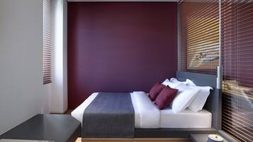 Un dormitorio moderno con cama, mesitas de noche y ventana con persianas.