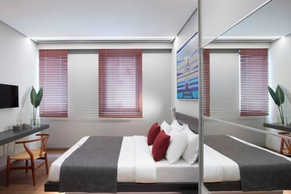Ein modernes Schlafzimmer mit einem Bett, einem Schreibtisch und einem großen Spiegel.