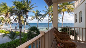 A balcony with wicker furniture overlooking a beach with palm trees and the ocean. - Ocean Front Condo - just steps from the beach!  Gold Standard Approved (San Pedro)
