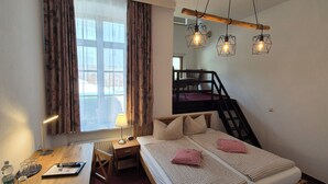 Un dormitorio con cama, escritorio, silla, lámpara y tres luces colgantes.