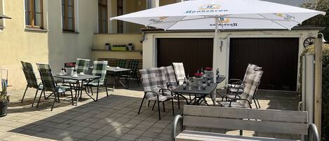 An outdoor patio with tables and chairs, a bench, and a large umbrella.