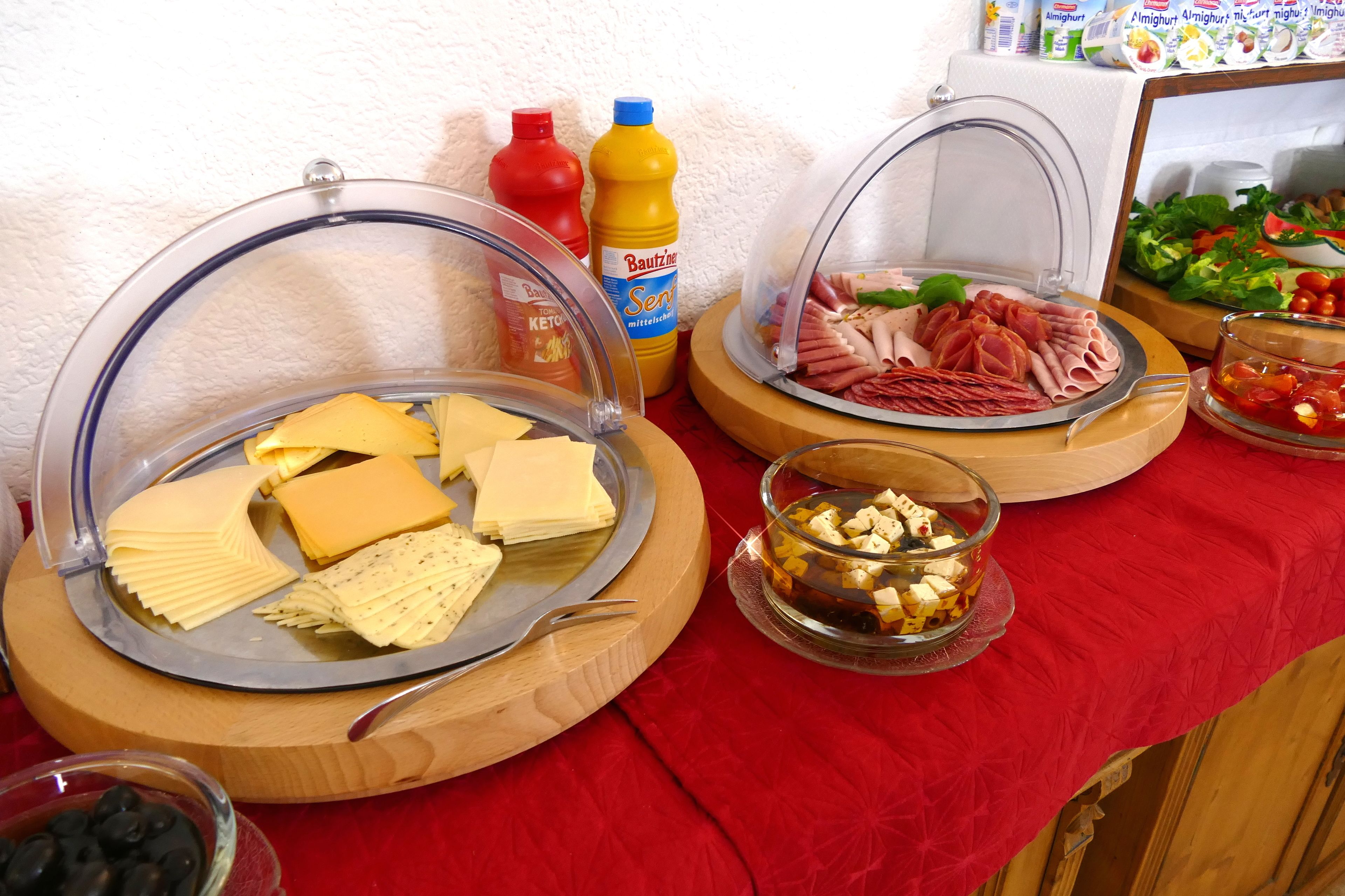 A buffet table with various food items including cheese, meats, and condiments.