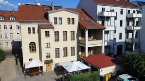 Un edificio de varios pisos con techo plano y un patio con mesas al aire libre.