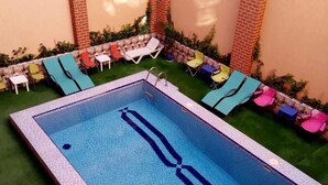 A rectangular swimming pool with a ladder, surrounded by a brick wall and a small grassy area. - Résidence Touristique Koutoubienne (Marrakech)