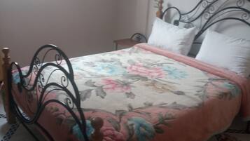 Una cama con colcha floral, cabecero de madera y alfombra roja.