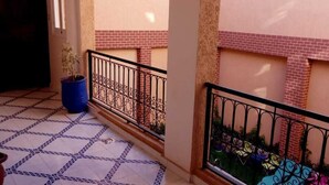 A balcony with patterned tiles, a potted plant, and a metal railing. - Résidence Touristique Koutoubienne (Marrakech)