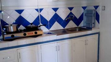 A kitchen with white cabinets, a blue and white tiled backsplash, a gas stove, and a water dispenser.