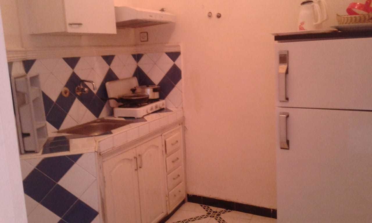 Una cocina compacta con estufa a gas, pileta y refrigerador.