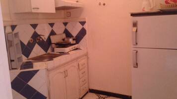 Una cocina compacta con estufa a gas, pileta y refrigerador.