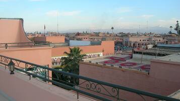 Eine Dachterrasse mit Blick auf die Stadt, mit einer Palme und gemusterten Bodenfliesen.