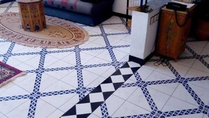 A living room with a patterned floor, a sofa, a small stool, and a decorative vase. - Résidence Touristique Koutoubienne (Marrakech)