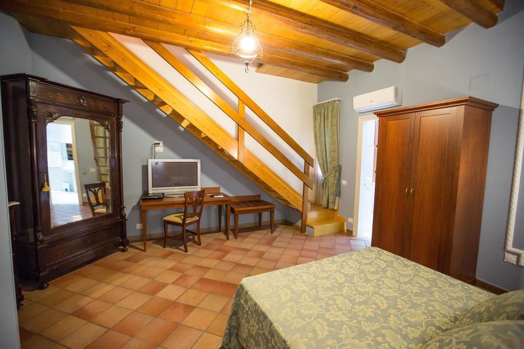 A bedroom with a bed, a desk with a chair, a television, a wardrobe, and a staircase.