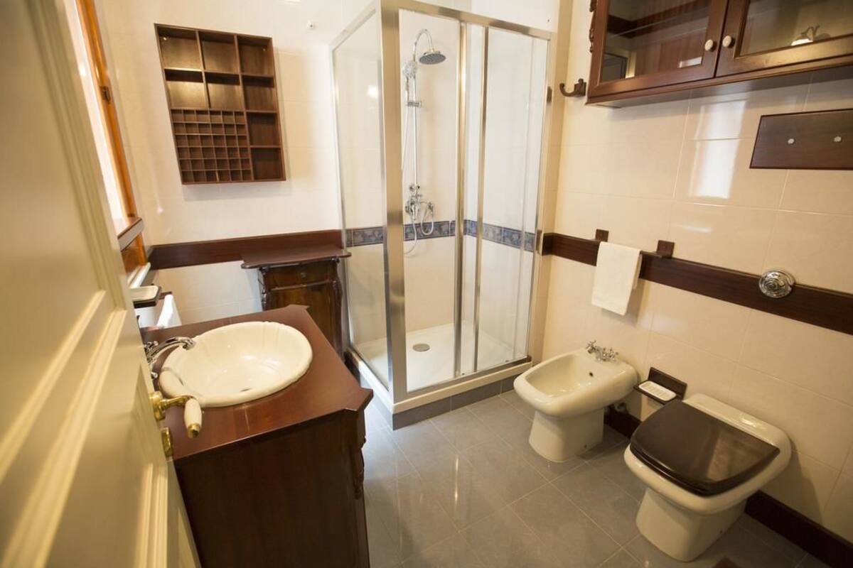 Un baño con ducha de vidrio, lavamanos, bidé e inodoro.