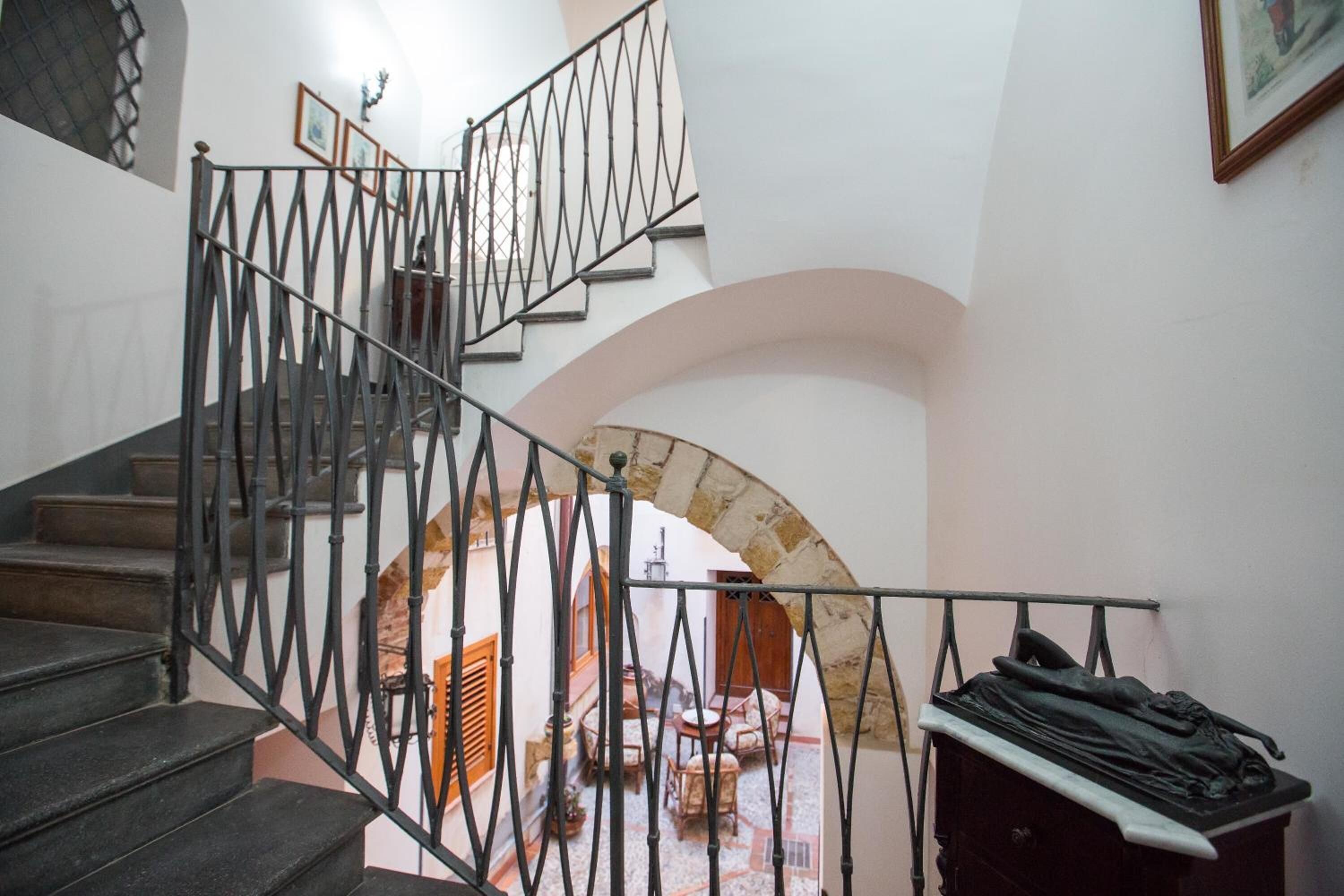 Eine Treppe mit schmiedeeisernem Geländer, das zu einer oberen Etage führt.
