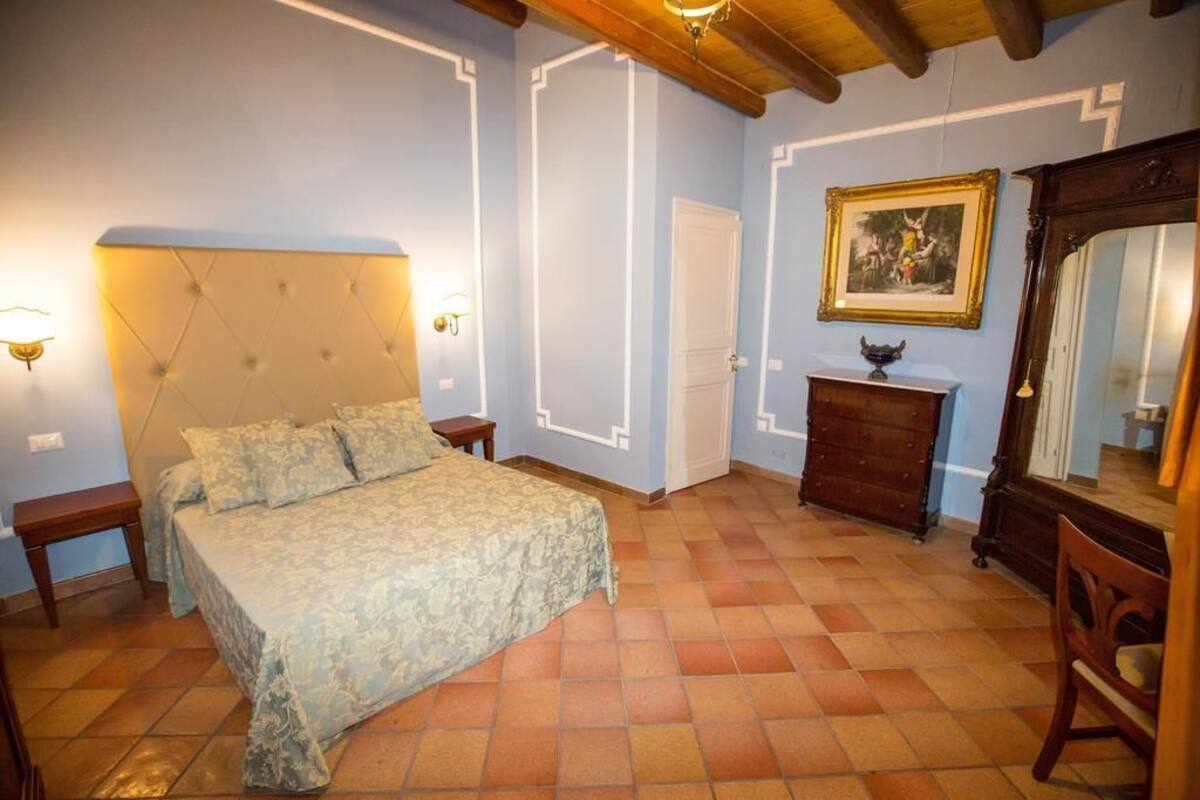 Un dormitorio con cama, mesitas de noche, cómoda, espejo y pared con diseño geométrico.
