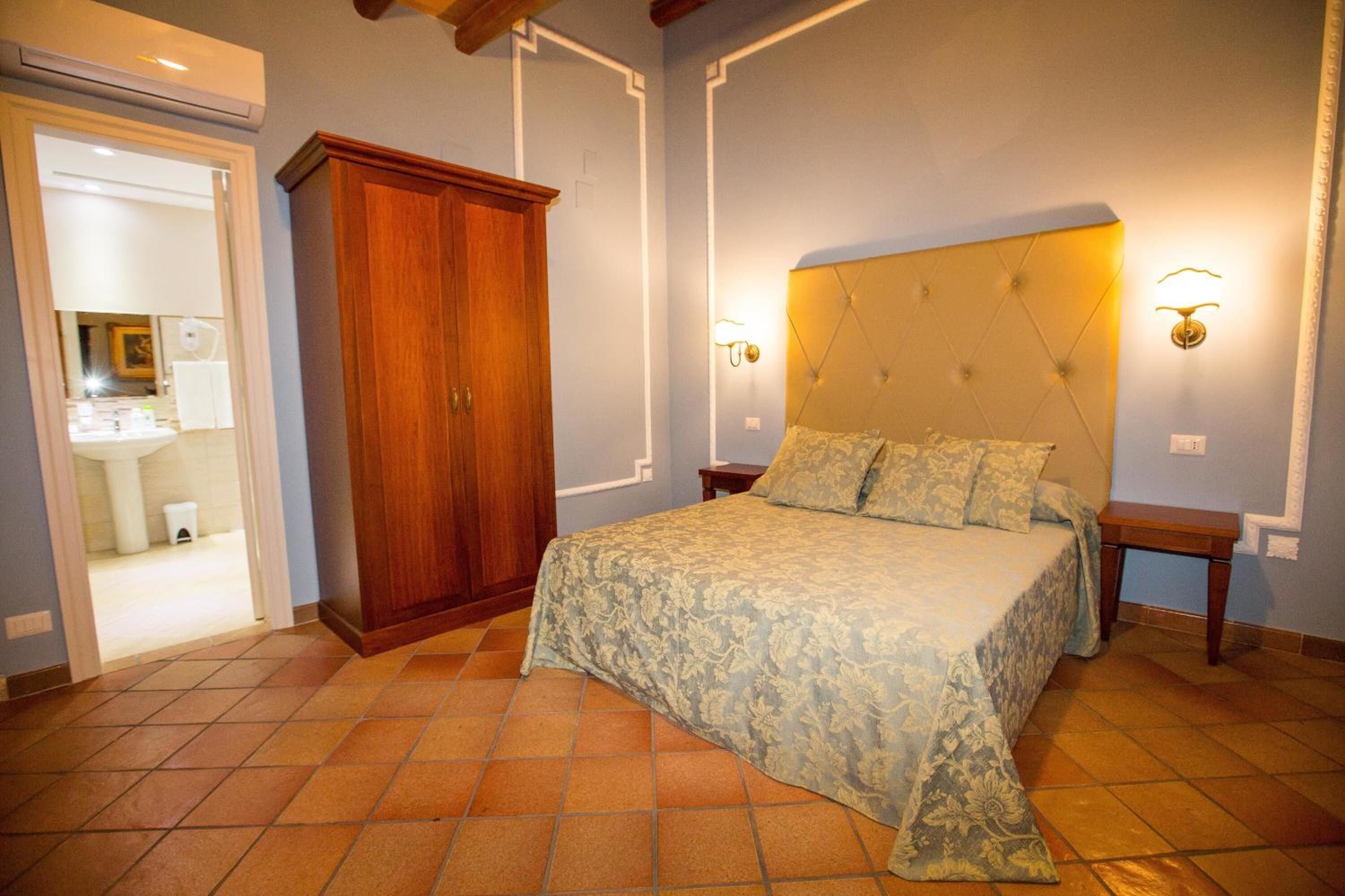 Una camera da letto con un letto, un armadio, un comodino e una lampada a parete.